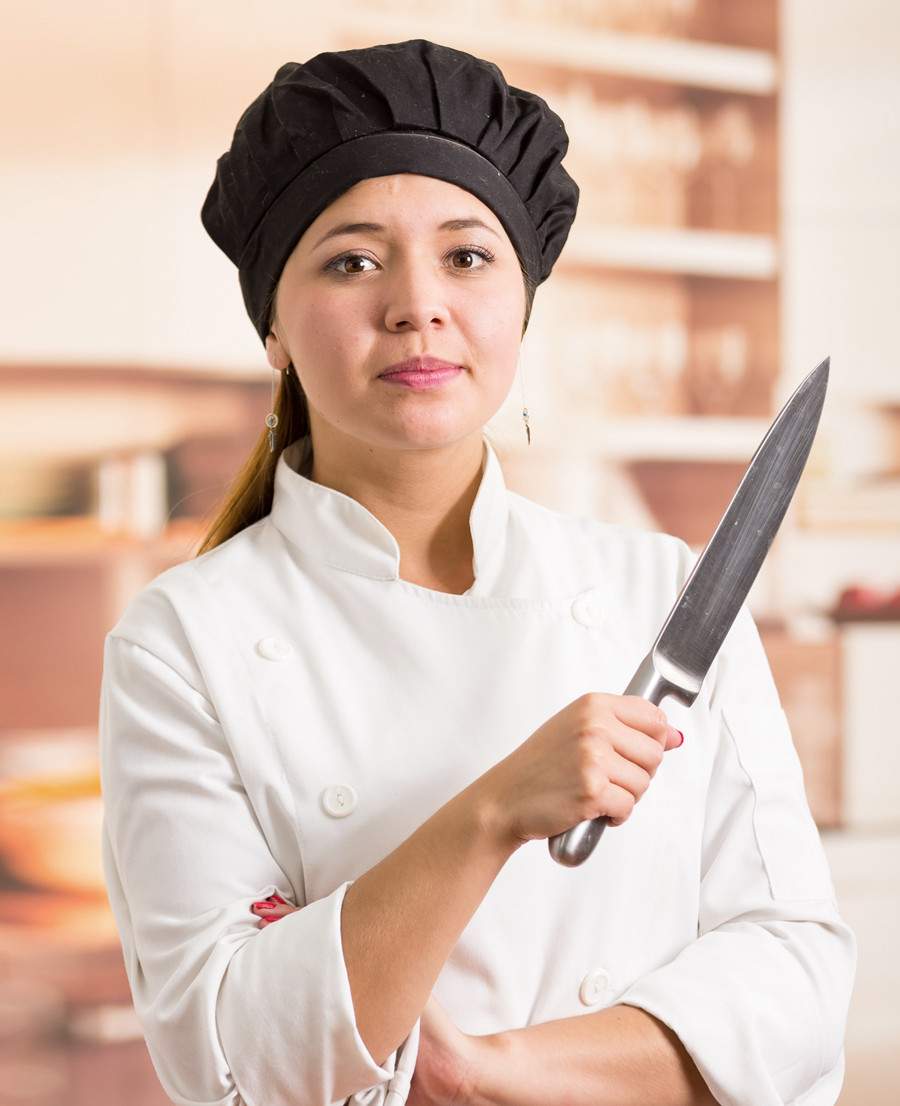 [caption: Payroll Deduction Service Available] Female chef holding a large butcher knife